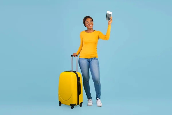 Feliz atractiva mujer afroamericana milenaria en pasaporte casual de bodega, boletos y maleta — Foto de Stock