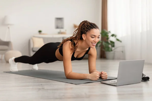 Nero femmina vicino computer portatile in piedi in plancia esercizio a casa — Foto Stock
