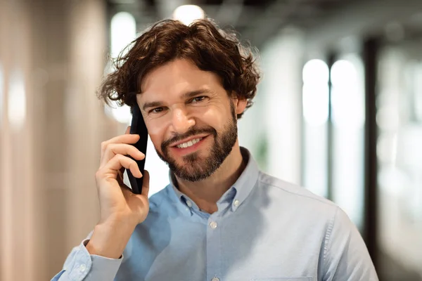 Uomo d'affari sorridente che lavora e parla al telefono in ufficio — Foto Stock