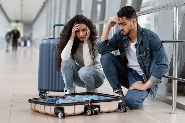 Oggetti mancanti. Frustrato coppia mediorientale in aeroporto guardando valigia aperta — Foto Stock