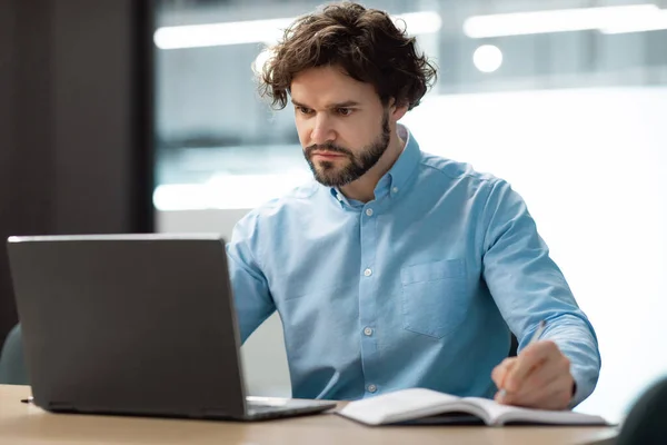 Retrato de homem focado usando laptop e escrita em notebook — Fotografia de Stock