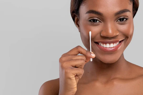 Usmívající se hezká mladá africká americká fena s perfektní kůže show bavlněné tampon izolované přes šedé pozadí — Stock fotografie