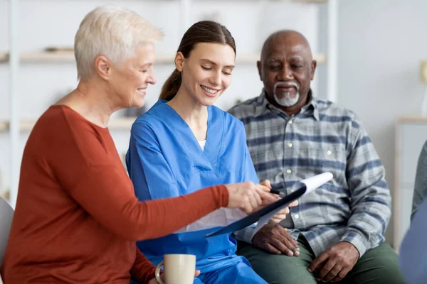 Jovem médica alegre conversando com pacientes seniores — Fotografia de Stock