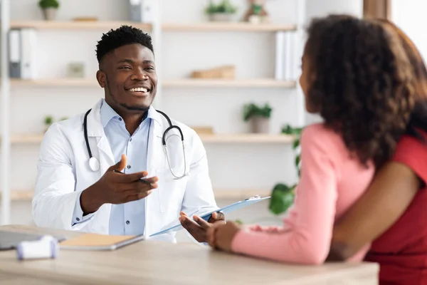 Fröhlicher afrikanisch-amerikanischer Arzt sammelt Anamnese von Patient — Stockfoto