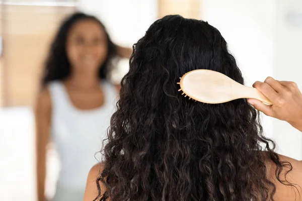 Curly Brunette Lady Brushing Her Long Beautiful Hair With Bamboo Comb