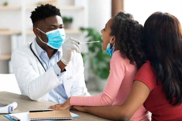 Médico afroamericano tomando una prueba de hisopo oral para niña —  Fotos de Stock