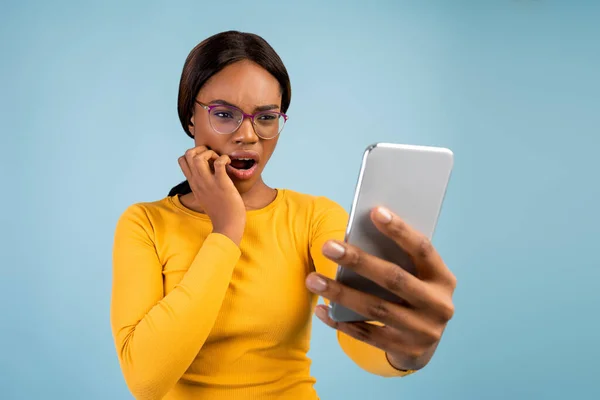Шокированная африканская женщина тысячелетия в очках с открытым ртом читает сообщение по телефону — стоковое фото