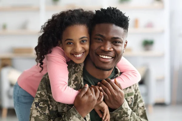 Портрет веселого чорношкірого дівчинки-підлітка, що обіймає батька солдата — стокове фото