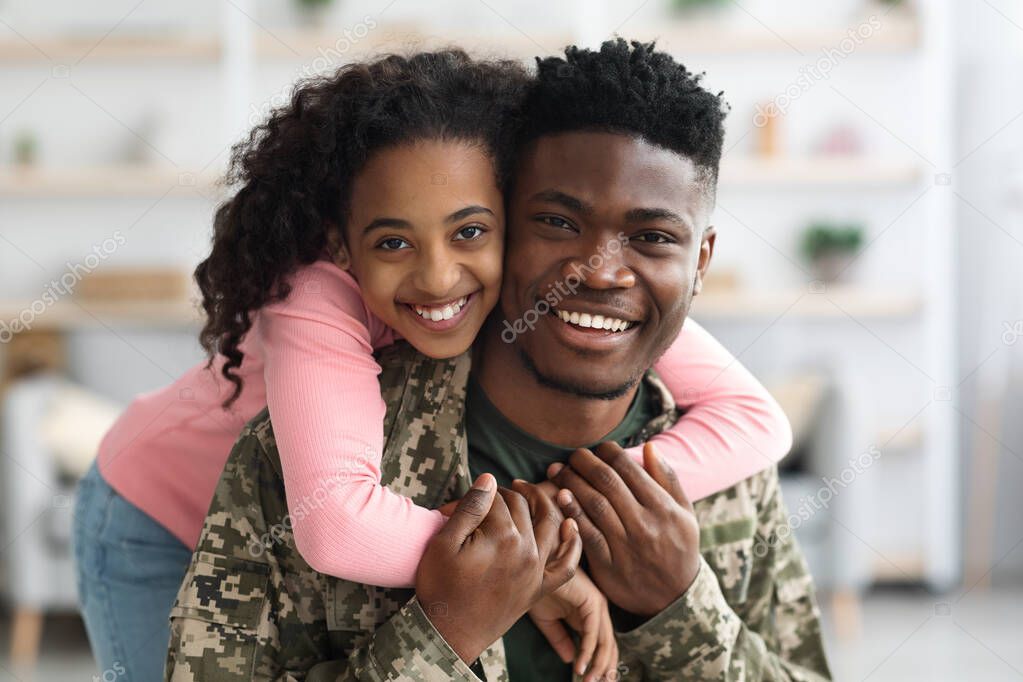Portrait of cheerful black teen girl hugging her daddy soldier