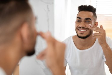 Cilt rutini. Çekici Orta Doğulu Adam Nemlendirici Krem Yüze Uyduruyor