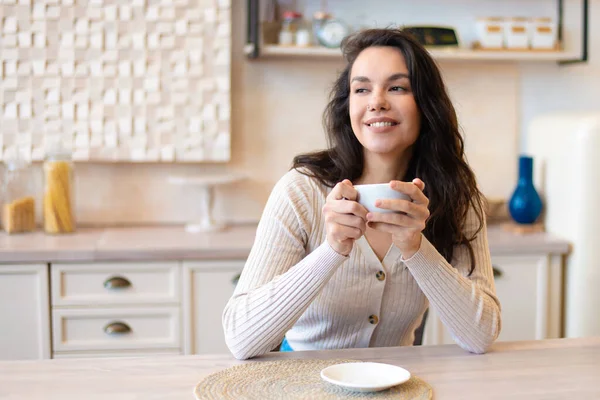 Buenos días, descansa y disfruta el fin de semana. Feliz mujer caucásica relajada bebiendo café en la cocina moderna y soñando — Foto de Stock