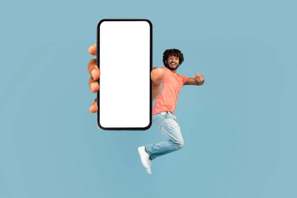 Happy eastern man jumping up and showing cell phone — Stock Photo, Image