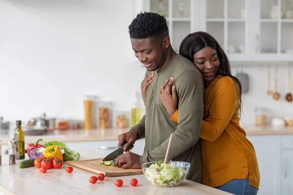 Amar a la esposa negra abrazando al marido mientras cocinan el almuerzo en la cocina — Foto de Stock