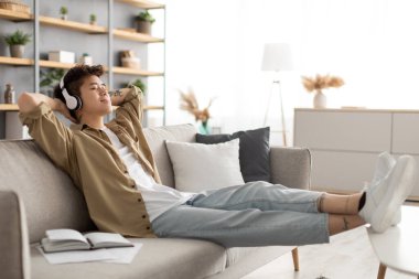 Kablosuz kulaklık takan mutlu Asyalı adam müzik dinliyor.