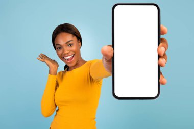 Tatmin olmuş, oldukça heyecanlı, sarı tişörtlü Afro-Amerikalı bir kadın. Akıllı telefon ve boş ekran.