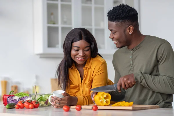 Portrait des conjoints noirs romantiques préparant ensemble des aliments sains dans la cuisine — Photo