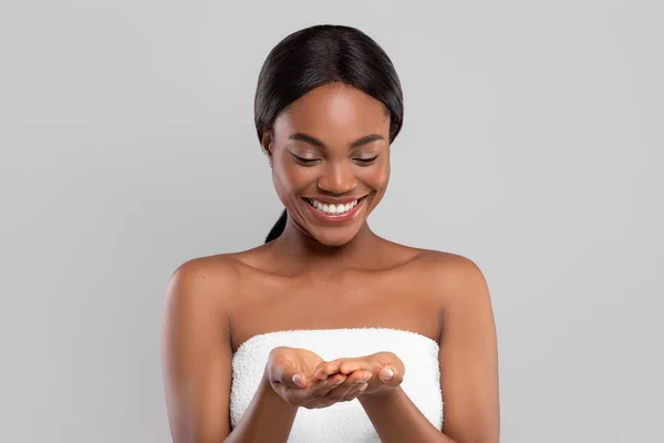 Cheerful pretty millennial african american female with perfect skin in towel looking at hands with free space — Stock Photo, Image