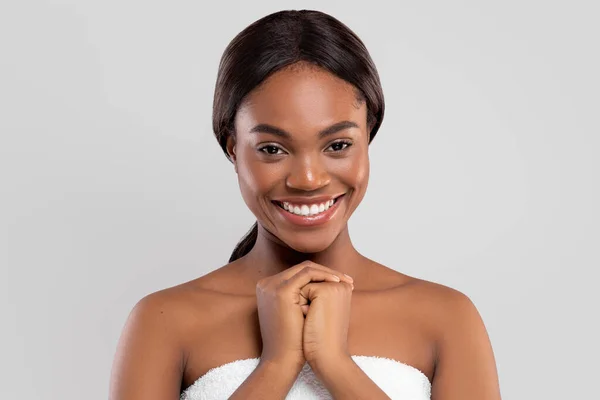 Cheerful pretty millennial african american woman with perfect skin in towel isolated on gray background, studio — Stock Photo, Image