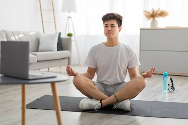 Asyalı adam bilgisayar kullanarak lotus pozisyonunda meditasyon yapıyor. — Stok fotoğraf