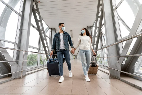 Молоді арабські пари У медичних масках ходять з валізами в аеропорту на алеї — стокове фото