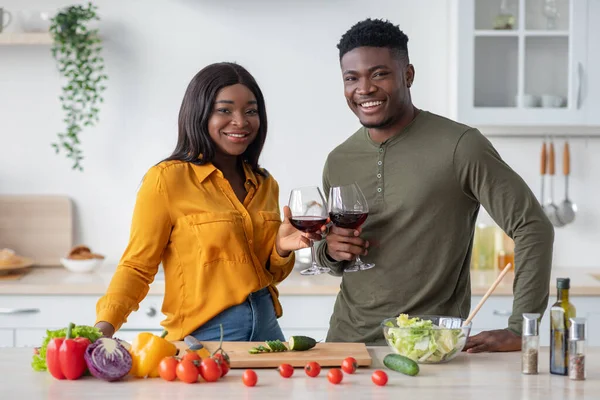 Negro pareja clavar vasos con vino en la cocina y sonriendo a la cámara, — Foto de Stock