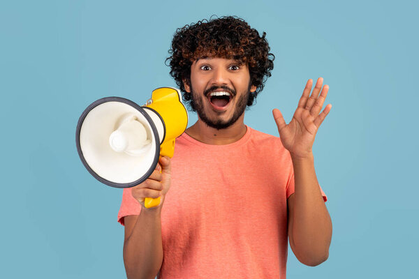 Surprised young indian guy with loudspeaker gesturing