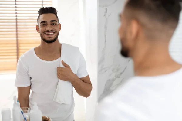 Concepto de autocuidado. Retrato de hombre árabe sonriente guapo posando en el interior del baño — Foto de Stock