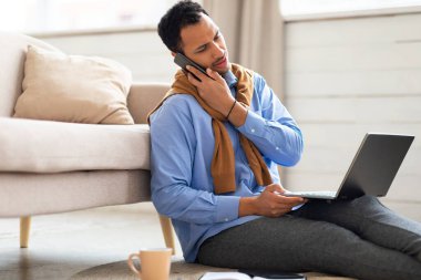Genç bir Arap evde çalışıyor ve telefonla konuşuyor.