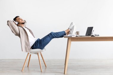 Asyalı adam kulaklık takıp müzik dinliyor.