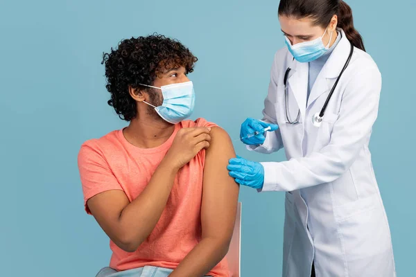 Curly man werd gevaccineerd tegen coronavirus op blauw — Stockfoto