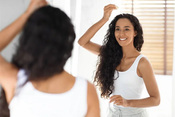 Huidverzorgingsproducten Mooie Millennial vrouwelijke toepassing hydraterende gezicht serum in de buurt van spiegel — Stockfoto
