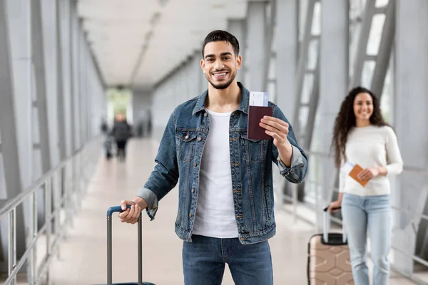 Servizio prenotazione voli. Uomo arabo in posa con passaporto e biglietti in aeroporto — Foto Stock