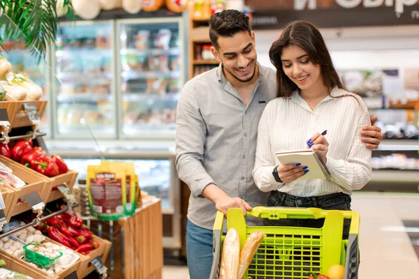スーパーマーケットで買い物リストを書く幸せな中東のカップル — ストック写真