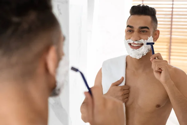 在浴室里，一个英俊的阿拉伯男子，光着身子在镜子前刮脸 — 图库照片