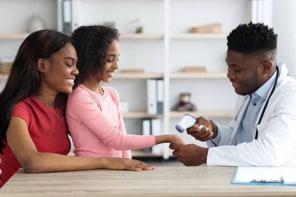 Pediatra afro-americano verificando a temperatura corporal da menina — Fotografia de Stock