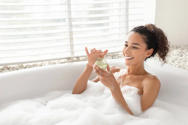 Mujer joven feliz tomando baño con espuma, usando crema corporal o mascarilla para el cabello en casa, espacio para copiar —  Fotos de Stock
