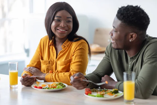 Romantiques conjoints noirs prendre le repas ensemble tout en étant assis à la table dans la cuisine — Photo