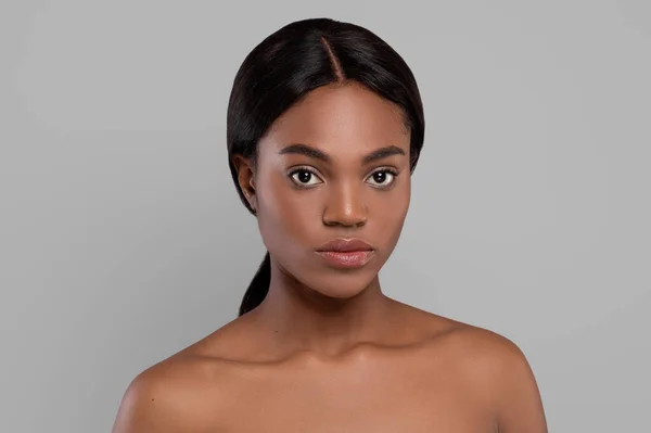 Ernste ruhige hübsche schwarze Frau mit perfekter Haut, die sich einsam fühlt und in die Kamera schaut, isoliert auf grauem Hintergrund — Stockfoto