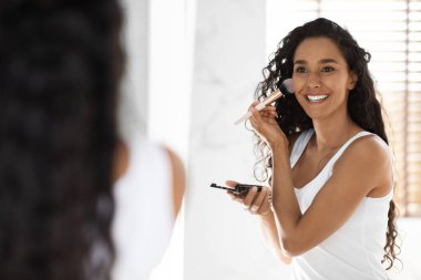 Günlük makyaj. Banyoda makyaj fırçasıyla allık süren Mutlu Arap Kadın