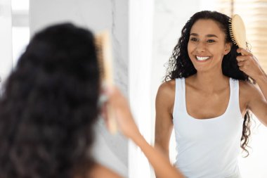 Genç ve güzel Orta Doğulu bir kadın Aynanın yanında duruyor ve saçlarını tarıyor