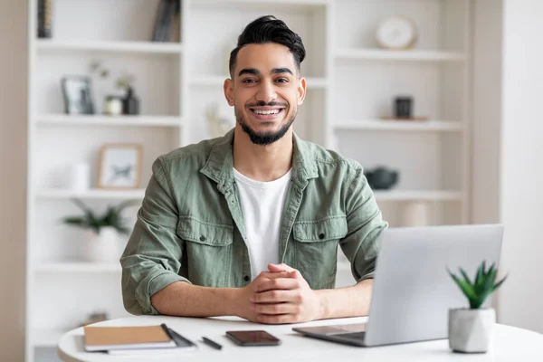 Fröhlich attraktiver arabischer Geschäftsmann mit Bart am Arbeitsplatz mit Laptop im Home Office Interieur — Stockfoto