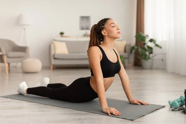 Donna afro-americana che fa esercizio di yoga per rafforzare la schiena al coperto — Foto Stock