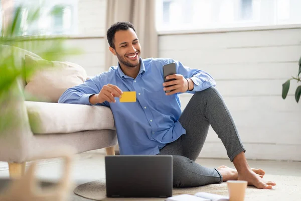 Lächelnder Araber mit Handy und Kreditkarte zu Hause — Stockfoto