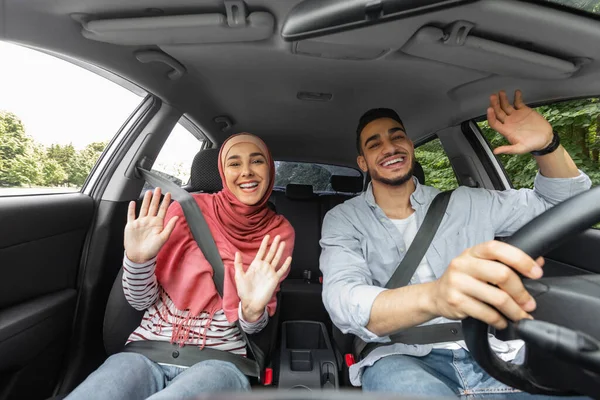 Glücklich lächelnde islamische Millennial-Dame im Hijab und Mann singen, tanzen und genießen die Fahrt im Auto — Stockfoto