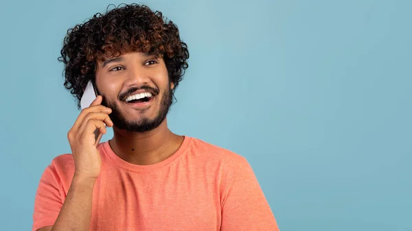 Primer plano de chico indio positivo teniendo conversación telefónica en azul — Foto de Stock