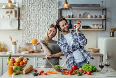 Sakallı ve dişili genç beyaz adamın organik sebzeleri ve yemekleri bir arada tutmasına sevindim.