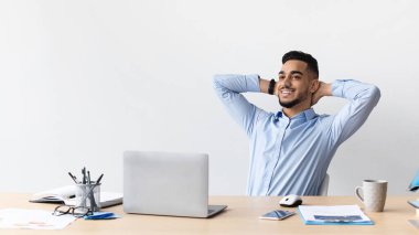 Gülümseyen bir Arap masaya yaslanıyor.