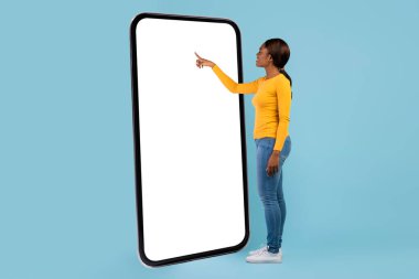 Gülümseyen Afrikalı genç bir Amerikalı kadın boş ekranda akıllı telefondan mesaj okuyor.