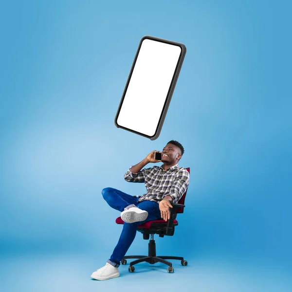 Afro-Amerikaanse man praten op telefoon zitten over blauwe achtergrond — Stockfoto