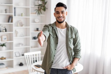 Bin yıllık mutlu, çekici, sakallı Arap adam selamlaşmak için elini uzatıyor ve kameraya bakıyor.